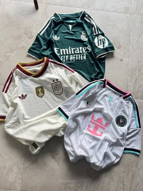 Green, cream and pale grey football jerseys arranged on a stone floor.